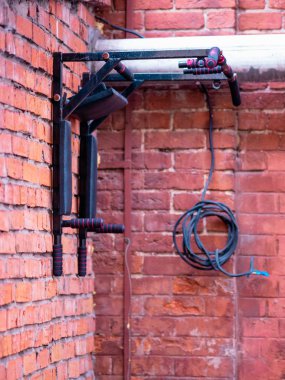 Bir evin kırmızı tuğla duvarına monte edilmiş yatay bir spor çubuğu.. 