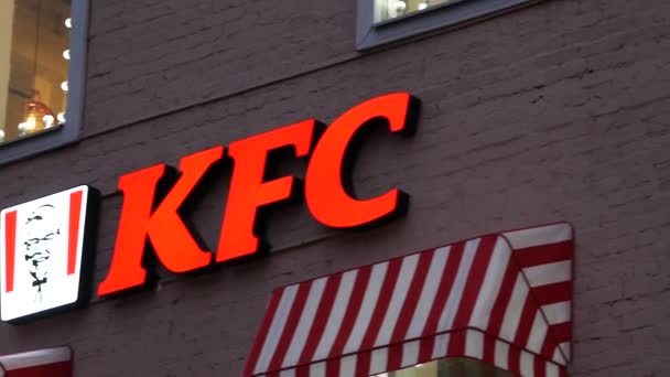 Logo KFC avec lumières rouges sur le mur de la maison en soirée. Fenêtres lumineuses lumineuses — Video