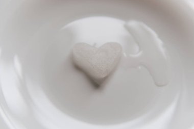 Karlı bir kalp beyaz bir tabakta erir. Gövde üzerinde kalp şeklinde kar. Buz gibi havada buz. Erimiş su küçük bir su birikintisinde toplanır. Sevgililer Günü konseptinde aşk