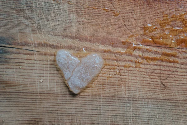 Snowy heart melts on a wooden table. Heart shaped snowball on a wooden kitchen cutting board. Ice in frosty weather. Melted water in the form of drops. Love on valentine's day concept — Stock Photo, Image