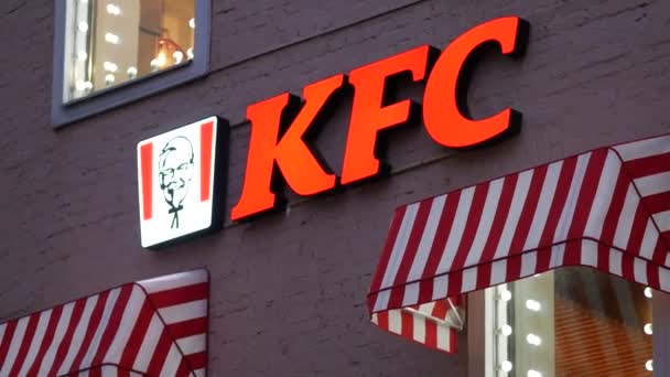 Logotipo KFC com luzes vermelhas na parede da casa à noite. Janelas brilhantes luminosas — Vídeo de Stock