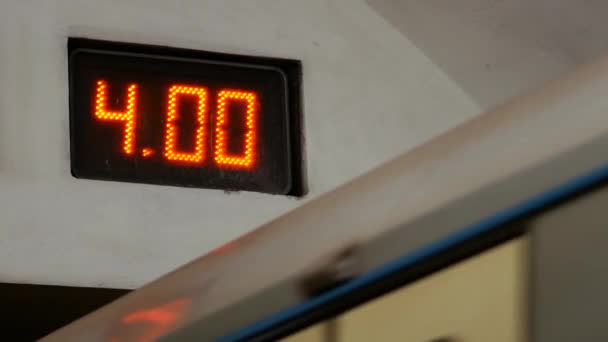Metro vlak vstupuje do tunelu metra pod elektronickou hodinovou tabulí. — Stock video