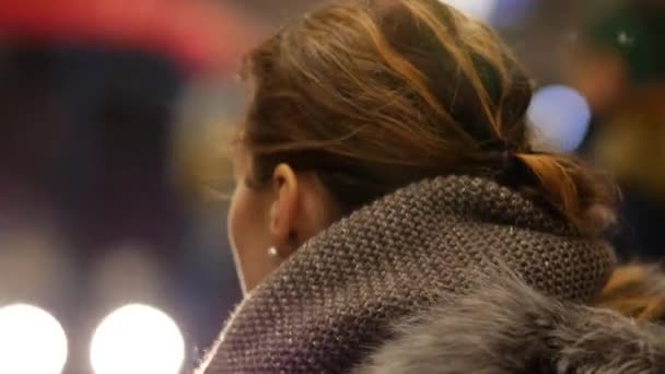 Jonge vrouw met vliegend haar in een winterjas staat en wacht op een metro — Stockvideo