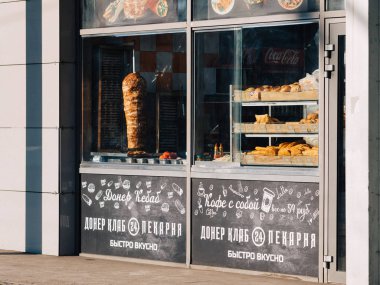 Moscow, Russia - February 8, 2020: Doner Club fast food signboard with a customer service window. Street showcase with product samples. Pies, shawarma and pastries. Coca-Cola Advertising