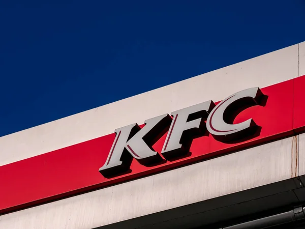 Moscow, Russia - February 8, 2020: Signboard of a fast-food restaurant KFC - an international chain of catering restaurants. Kentucky Fried Chicken logo on a building facade against a bright blue sky. — Stock Photo, Image