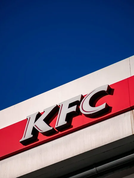 Moscow, Russia - February 8, 2020: Signboard of a fast-food restaurant KFC - an international chain of catering restaurants. Kentucky Fried Chicken logo on a building facade against a bright blue sky. — Stock Photo, Image