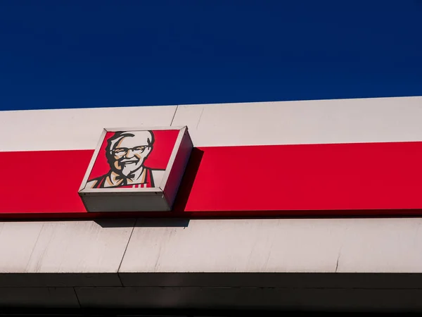 Moscow, Russia - February 8, 2020: Signboard of a fast-food restaurant KFC - an international chain of catering restaurants. Kentucky Fried Chicken logo on a building facade against a bright blue sky. — Stock Photo, Image