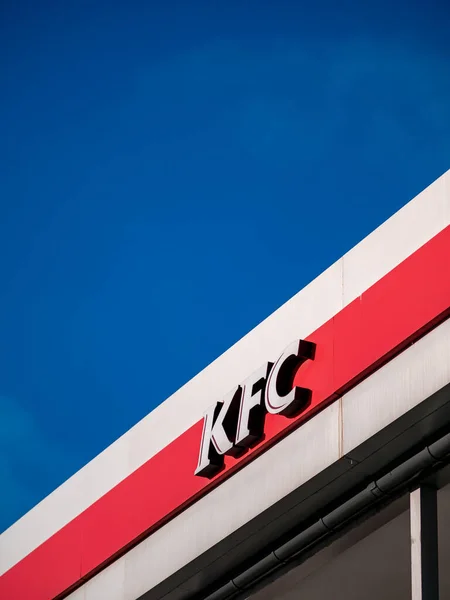 Moscow, Russia - February 8, 2020: Signboard of a fast-food restaurant KFC - an international chain of catering restaurants. Kentucky Fried Chicken logo on a building facade against a bright blue sky. — Stock Photo, Image