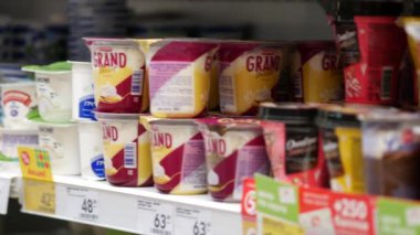 Jars of yogurt and milk desserts. Sour cream in plastic cups. Pyaterochka shop