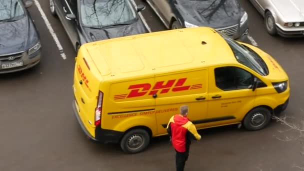 Dhl Deutsche Post futár sárga-piros egyenruhában a kisbusz közelében, céglogókkal — Stock videók