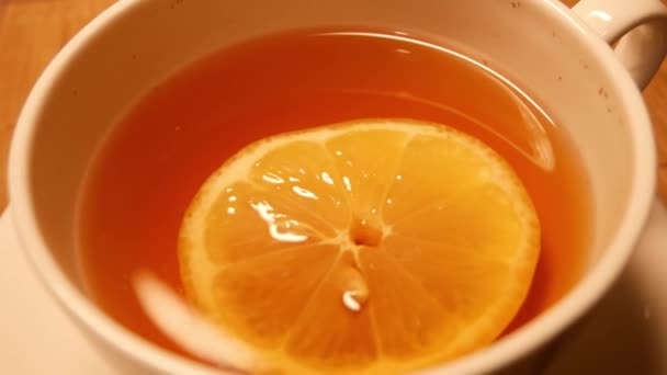 Thé au citron au ralenti dans une tasse blanche. Flotteur jaune citron à la surface — Video