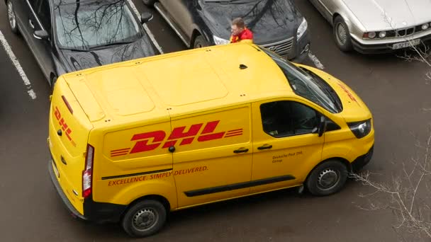 DHL Deutsche Post courier en uniforme amarillo-rojo cerca de minivan con logotipos de la empresa — Vídeos de Stock