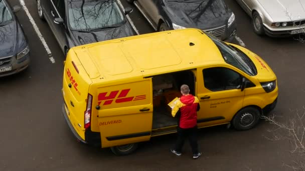 Dhl Deutsche Post futár sárga-piros egyenruhában a kisbusz közelében, céglogókkal — Stock videók