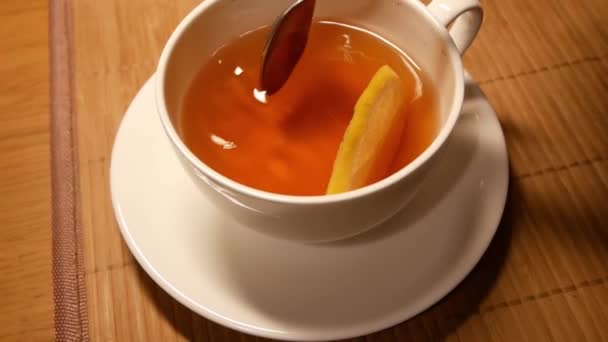 Lassú citromos tea fehér pohárban. Sárga citrom mozog a felszínen — Stock videók