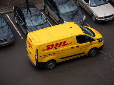 Moskova, Rusya - 11 Mart 2020: Dhl Deutsche Post şirket logolu minivan yakınlarında sarı-kırmızı üniformalı kurye. Dhl International Gmbh, dünyanın en büyük kurye, paket ve ekspres posta servisidir.