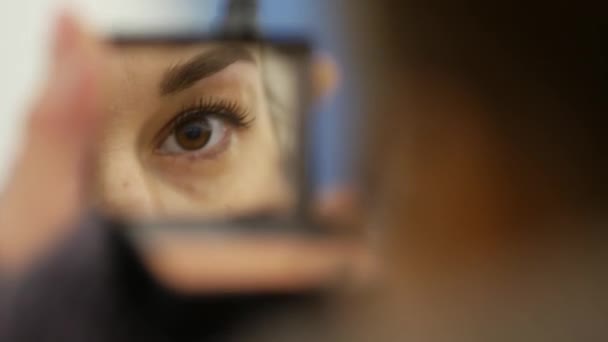 Mädchen in Winterjacke schminkt sich und streicht sich in U-Bahn-Lobby die Augenbrauen — Stockvideo