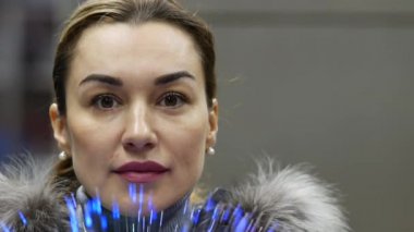 Genç ve güzel bayan, izleyiciye parlak fiber optik ipliklerden bakıyor.