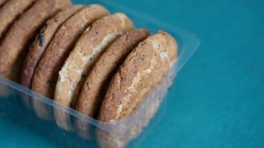 Yulaf ezmeli kurabiyeler şeffaf açık plastik tepside yatar. Erkek eli tatlı kurabiyeleri alır. Aşırı yeme ve karbonhidrat zengini gıdaları kötüye kullanma kavramı. Kan insülin seviyesini yükselten glisemik gıdalar