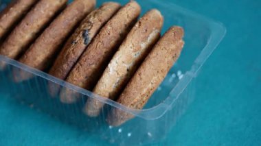 Yulaf ezmeli kurabiyeler şeffaf açık plastik tepside yatar. Erkek eli tatlı kurabiyeleri alır. Aşırı yeme ve karbonhidrat zengini gıdaları kötüye kullanma kavramı. Kan insülin seviyesini yükselten glisemik gıdalar