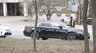 Polis devriyesi, durdurulan siyah arabanın sürücüsünün belgelerini kontrol ediyor.