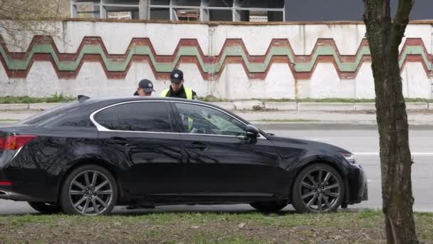 Gli ufficiali di pattuglia di polizia controllano documenti di conducente di auto nera fermata — Video Stock