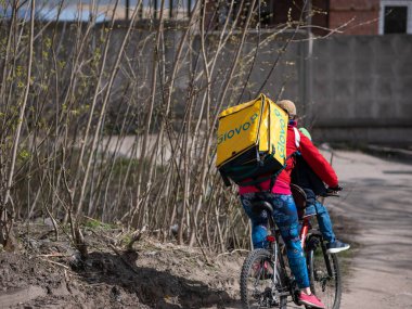 Dnipro, Ukrayna - 27 Mart 2020: GLOVO teslimatçı kadın kurye bisikletli sarı termal çantalı müşteri siparişleri. Şehir koronavirüs zatürresi tehdidi nedeniyle karantinaya alındı.