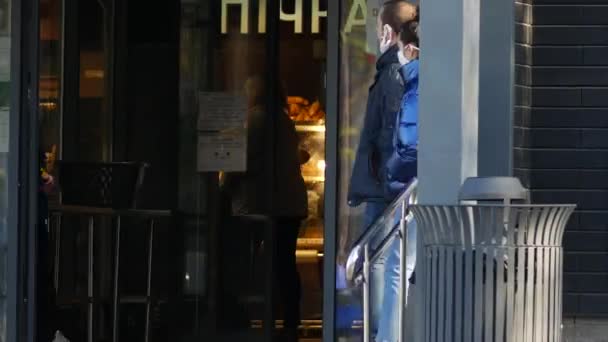 Couple de fille et mec portent un masque facial sur la rue en passant par l'entrée du magasin ATB — Video