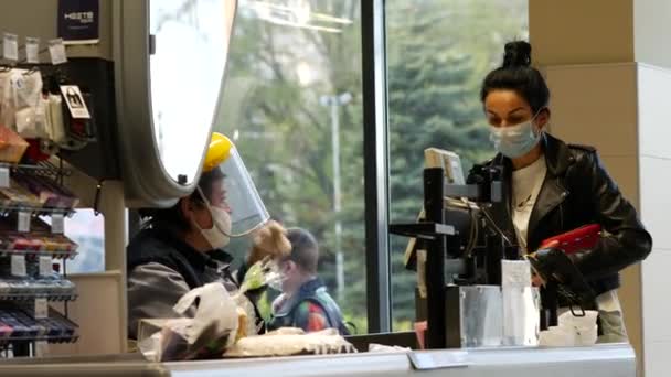 女性キャッシャー着用フェイスマスクとガラスシールドでATBスーパーマーケットによりcovid-19 — ストック動画
