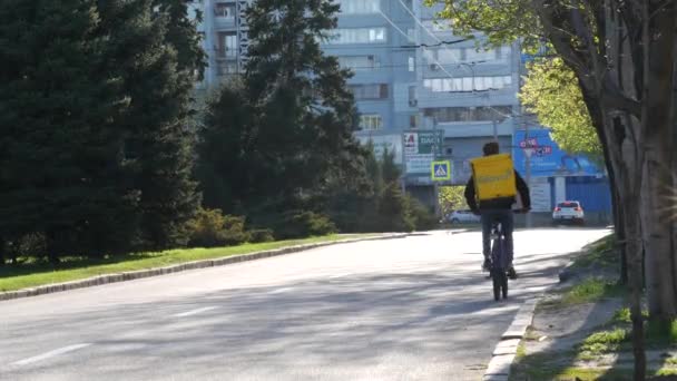 Dostawca GLOVO kurier na rowerze z markowym żółtym plecakiem termicznym dostawy — Wideo stockowe