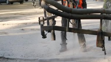 İşçiler yol kenarına asfalt çipleri püskürterek kaldırıma küçük onarımlar yapıyorlar