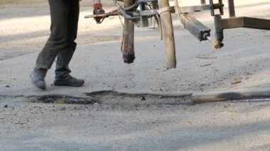 İşçiler yol kenarına asfalt çipleri püskürterek kaldırıma küçük onarımlar yapıyorlar