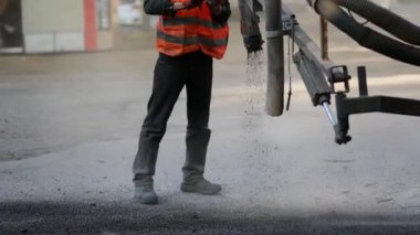 İşçiler yol kenarına asfalt çipleri püskürterek kaldırıma küçük onarımlar yapıyorlar