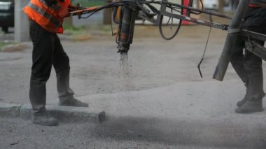 İşçiler yol kenarına asfalt çipleri püskürterek kaldırıma küçük onarımlar yapıyorlar