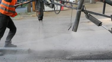 İşçiler asfalt çiplerini çukurlara püskürterek kaldırıma küçük onarımlar yapıyorlar.