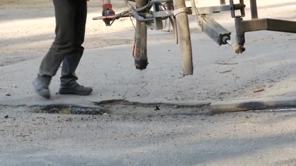 Werknemers voeren kleine reparaties aan bestrating door het spuiten van asfalt chips op de weg — Stockvideo