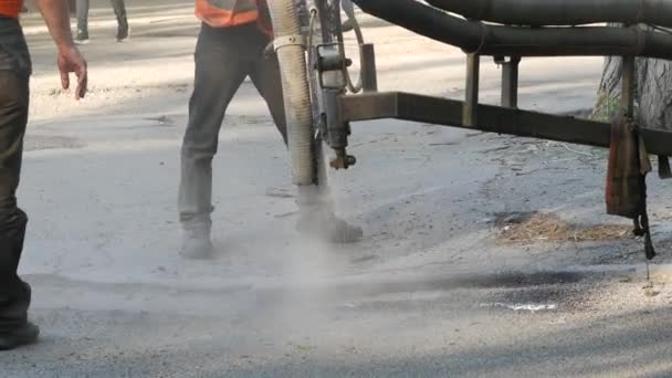 Werknemers voeren kleine reparaties aan bestrating door het spuiten van asfalt chips in putten — Stockvideo