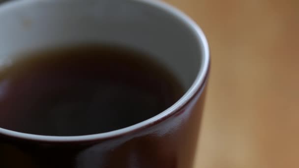 La vapeur monte sur une boisson pourpre versée dans une tasse en porcelaine brune. Thé ou café — Video