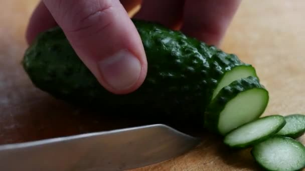 Свіжий зелений огірок кладуть на кухню дерев'яною обробною дошкою і нарізають — стокове відео