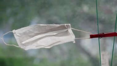 Koruyucu tıbbi maske, platin sicimin mandalına asılır. PPE