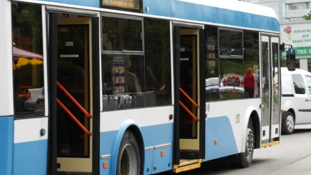 Trolejbus odjíždí ze zastávky. Žena si sundává masku na ulici za koncem cesty — Stock video
