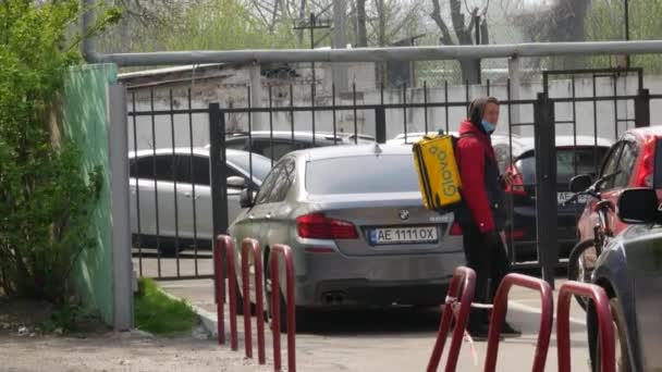 Kurier dostawy GLOVO z markowym żółtym plecakiem termicznym na zamówienie klienta — Wideo stockowe