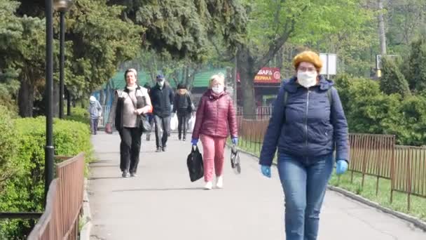 Люди ходять вулицею міста і носять маску обличчя та рукавички латексу. Карантин — стокове відео
