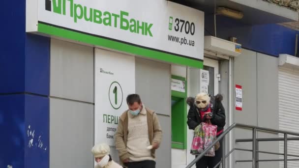 Egy férfi maszkot visel, és latex kesztyű áll az ATM-nél a Privat bank mellett. — Stock videók