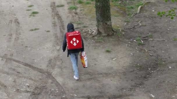 Koerier van de postdienst Nova Poshta met rode rugzak staat in de buurt van huis — Stockvideo