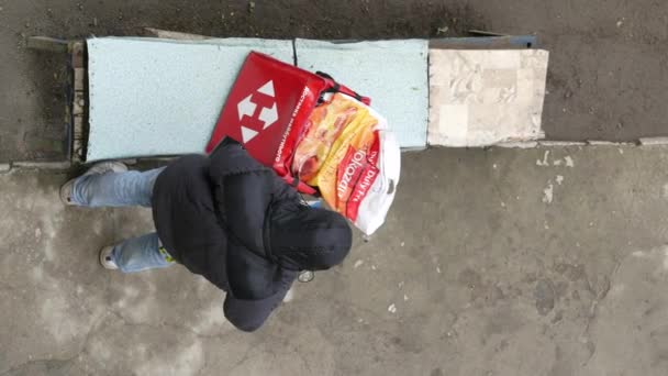 Courier of postal service Nova Poshta with red knapsack stands near house — Stock Video