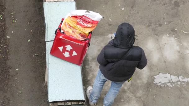 Kurier usług pocztowych Nova Poshta z czerwonym plecakiem stoi w pobliżu domu — Wideo stockowe