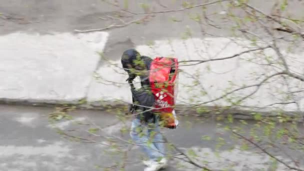 Kurir layanan pos Nova Poshta dengan ransel merah berdiri di dekat rumah — Stok Video