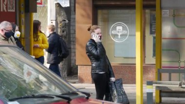 İnsanlar sosyal mesafeyi gözlemler ve toplu taşıma durağında dururlar. Sıcak güneşli