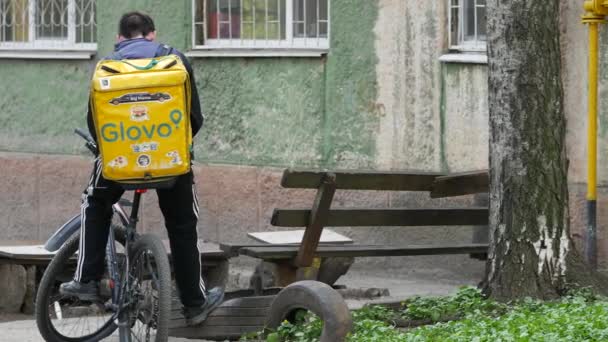Kurier dostawy GLOVO z markowym żółtym plecakiem termicznym na zamówienie klienta — Wideo stockowe