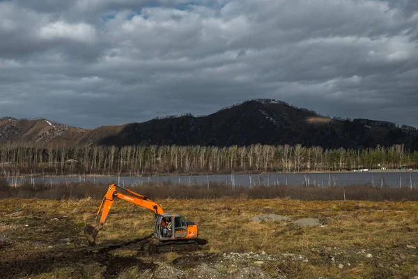 Manzherok, Altai Krai, Russia - 27 Οκτωβρίου 2019: Εκσκαφέας σκάβει γη κοντά στη λίμνη Manzherok — Φωτογραφία Αρχείου